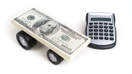 Money stack on plastic wheels next to calculator