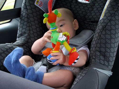Baby in a car seat playing with a toy