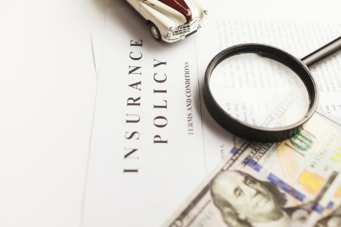 Magnifying glass on auto insurance paper work.