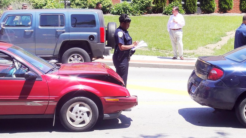 Two cars after a rear-end accident by a policewoman filling out a report.