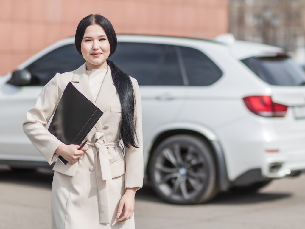 Woman in beige corporate clothes holding a black folder.