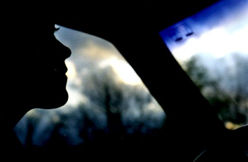 A silhouette of a person driving with a sunset behind them.