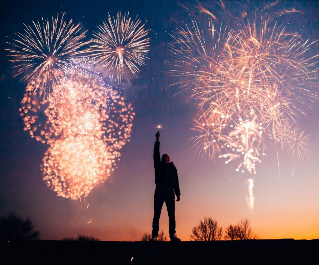 Man With Fireworks behind in on the dusk skyline