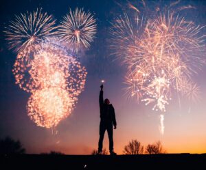 Man With Fireworks behind in on the dusk skyline