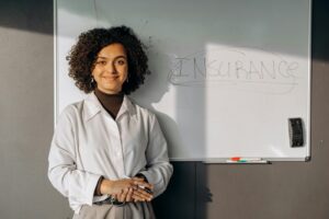 Woman Standing Near a White Board, with Insurance written on it