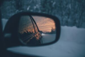 Mirror or a car, showing snow and another car